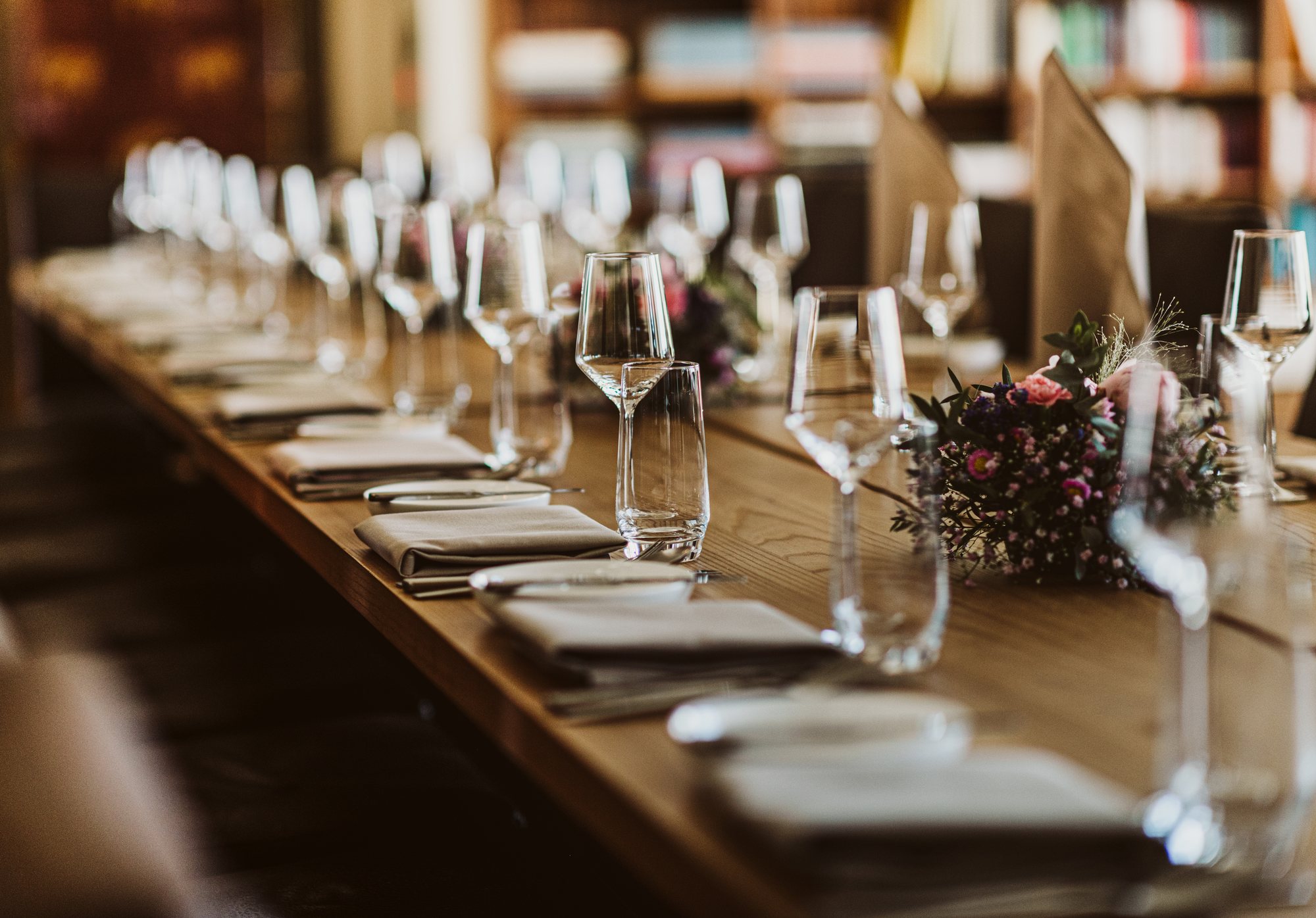 Une grande table dressée avec verres et fleurs au PallCafé